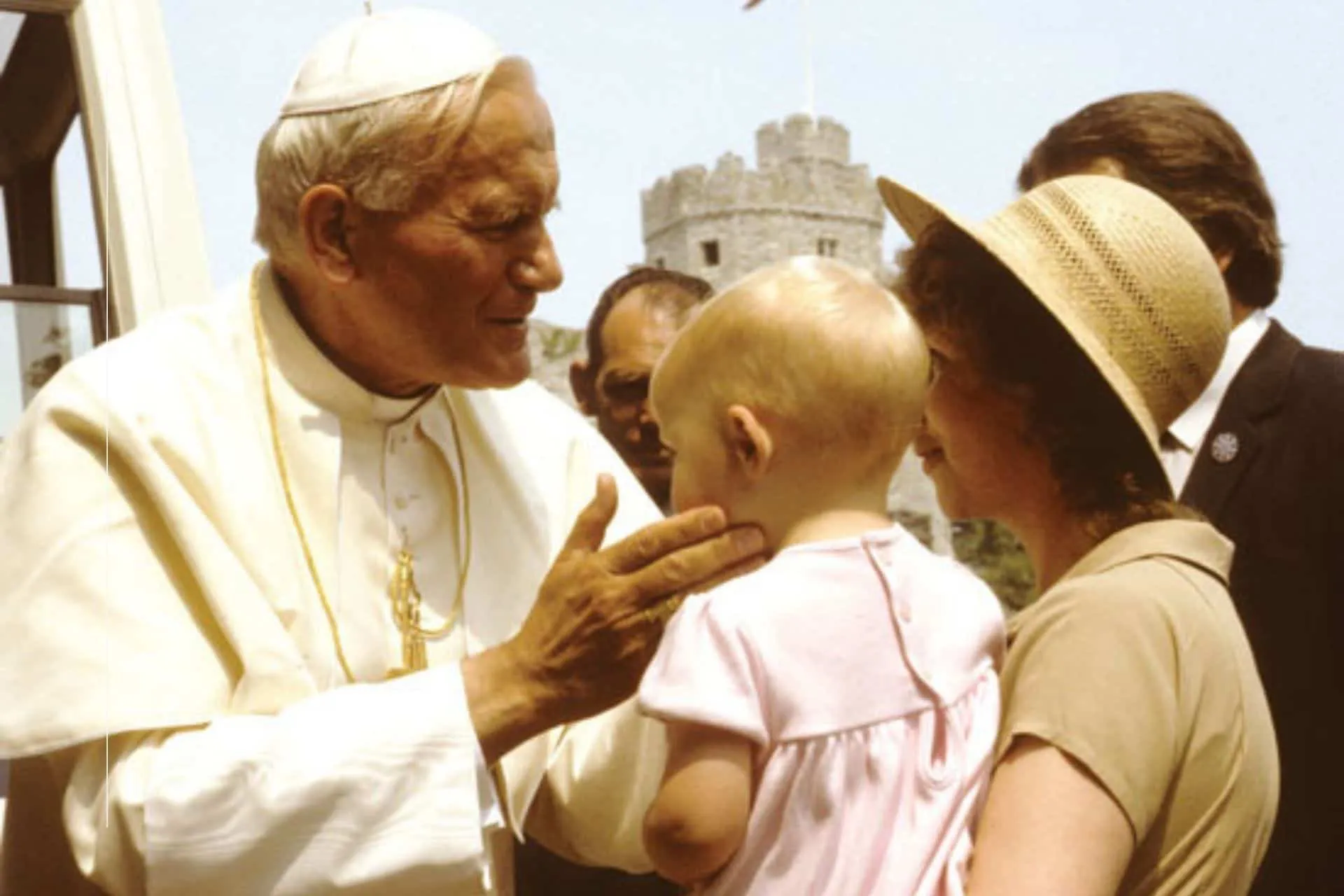 San Juan Pablo II acariciando a un bebé en brazos de su madre